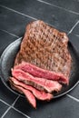 Grilled Flap or Flank Steak, sliced on a plate. Black background. Top view Royalty Free Stock Photo