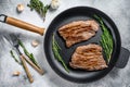 Grilled flat iron and flank steaks in a pan. Marble beef meat. Gray background. Top view