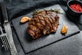 Grilled Flat Iron steak on a stone Board, marbled beef. Black background. Top view