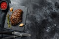 Grilled Flat Iron steak on a stone Board, marbled beef. Black background. Top view. Copy space