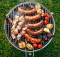 Grilled food. Grilled pork sausage, bacon and vegetables on the grill plate, top view.