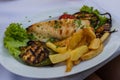 Grilled fresh squid on white plate with chips and vegetables Royalty Free Stock Photo