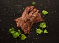 Grilled fried marbled beef slices on black slate background