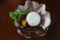 Grilled gourami or Gurame bakar with red barbeque sauce, rice, vegetables, tofu, and tempeh on a rattan plate