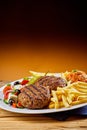 Grilled Greek bifteki with salad and French fries Royalty Free Stock Photo