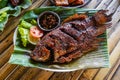 Grilled gurami or grilled gurame with red barbecue sauce, vegetables and chili sauce served on banana leaves