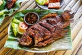 Grilled gurami or grilled gurame with red barbecue sauce, vegetables and chili sauce served on banana leaves