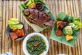 Grilled gurami or grilled gurame with red barbecue sauce, vegetables and chili sauce served on banana leaves