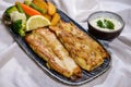 Grilled Hamour fish with fried veggies, lemon and salad served in dish isolated on food table top view of middle east spices