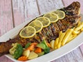 GRILLED HAMOUR Fish with gravy, lemon slice and tomato served in dish isolated on table closeup top view of grilled seafood Royalty Free Stock Photo