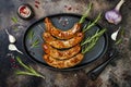 Grilled homemade rosemary sausages skewers on iron frying pan over rustic dark stone kitchen table. Top view, flat lay. Royalty Free Stock Photo