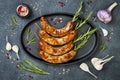 Grilled homemade rosemary sausages skewers on iron frying pan over rustic dark stone kitchen table. Top view, flat lay. Royalty Free Stock Photo