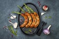 Grilled homemade rosemary sausages skewers on iron frying pan over rustic dark stone kitchen table. Top view, flat lay. Royalty Free Stock Photo