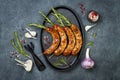 Grilled homemade rosemary sausages skewers on iron frying pan over rustic dark stone kitchen table. Top view, flat lay. Royalty Free Stock Photo