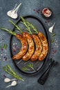 Grilled homemade rosemary sausages skewers on iron frying pan over rustic dark stone kitchen table. Top view, flat lay. Royalty Free Stock Photo