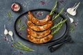 Grilled homemade rosemary sausages skewers on iron frying pan over rustic dark stone kitchen table. Top view, flat lay. Royalty Free Stock Photo