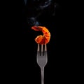 Grilled hot shrimp on a fork on a black background