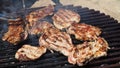 Grilled juicy meat pork steaks in burning coals on a barbecue grill, white smoke. Crispy crust. Tasty steak with Royalty Free Stock Photo