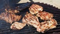 Grilled juicy meat pork steaks in burning coals on a barbecue grill, white smoke. Crispy crust. Tasty steak with Royalty Free Stock Photo