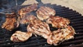 Grilled juicy meat pork steaks in burning coals on a barbecue grill, white smoke. Crispy crust. Tasty steak with blood and fried Royalty Free Stock Photo