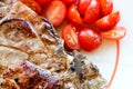 Grilled juicy pork meat steak with vegetables cherry tomatoes on a white plate Royalty Free Stock Photo