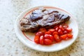 Grilled juicy pork meat steak with vegetables cherry tomatoes on a white plate Royalty Free Stock Photo