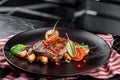 Grilled juicy steak with grilled mushrooms, tomatoes and cranberries on a dark plate and rad napkin on a dark background Royalty Free Stock Photo