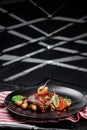 Grilled juicy steak with grilled mushrooms, tomatoes and cranberries on a dark plate and rad napkin on a dark background Royalty Free Stock Photo