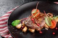 Grilled juicy steak with grilled mushrooms, tomatoes and cranberries on a dark plate and rad napkin on a dark background Royalty Free Stock Photo