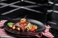 Grilled juicy steak with grilled mushrooms, tomatoes and cranberries on a dark plate and rad napkin on a dark background Royalty Free Stock Photo