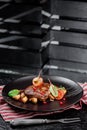 Grilled juicy steak with grilled mushrooms, tomatoes and cranberries on a dark plate and rad napkin on a dark background Royalty Free Stock Photo