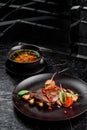 Grilled juicy steak with grilled mushrooms, tomatoes and cranberries on a dark round plate Royalty Free Stock Photo