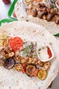 Grilled kebab with pita bread and vegetables on tray in summer fast food street cafe