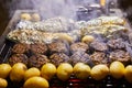 Grilled kebabs potato and fish in foil with smoke from the grill. BBQ party