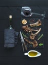 Grilled lamb chops. Rack of Lamb with garlic, rosemary, spices on slate tray, wine glass, oil in a saucer and bottle Royalty Free Stock Photo