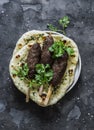 Grilled lamb kebab and flatbreads with garlic and herbs on a dark background, top view Royalty Free Stock Photo