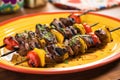 grilled lamb kebabs on skewers on a yellow plate