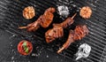 Grilled lamb ribs meat or rib eye with tomato sauce over the coals on a barbecue, dark background. Top view