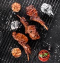 Grilled lamb ribs meat or rib eye with tomato sauce over the coals on a barbecue, dark background. Top view Royalty Free Stock Photo