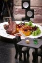 Grilled lamb ribs served with grilled corn, salat, bbq sauce, on a white plate