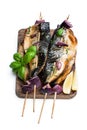 Grilled mackerel and red onion on skewers on wooden board isolated on white Royalty Free Stock Photo