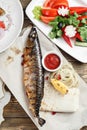 Grilled mackerel and a salad of fresh vegetables. Serving on a wooden Board on a rustic table. Barbecue restaurant menu Royalty Free Stock Photo