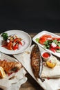 Grilled mackerel and sea bass. Salad of fresh vegetables. Serving on a wooden Board on a rustic table. Barbecue Royalty Free Stock Photo