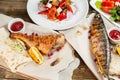 grilled mackerel and sea bass. Salad of fresh vegetables. Serving on a wooden Board on a rustic table. Barbecue Royalty Free Stock Photo