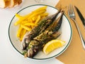 Grilled mackerels with French fries, lemon and sauce Royalty Free Stock Photo