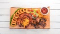 Grilled meat on the board. Sausage, ribs and fresh vegetables. On a wooden table. Royalty Free Stock Photo