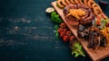 Grilled meat on the board. Sausage, ribs and fresh vegetables. On a wooden table. Royalty Free Stock Photo