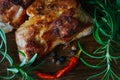 Grilled meat pieces dark crust on the outside and fresh rosemary on a wooden cutting board background.