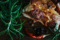 Grilled meat pieces dark crust on the outside and fresh rosemary on a wooden cutting board background.