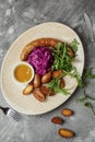 Grilled meat sausages and baked potatoes with vegetables on grey clay background. Royalty Free Stock Photo